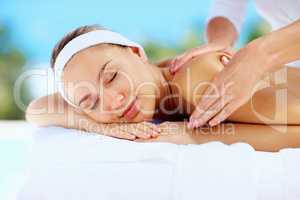 Relaxed young lady receiving shoulder massage from a masseuse. Relaxed young woman receiving shoulder massage from a professional masseuse.