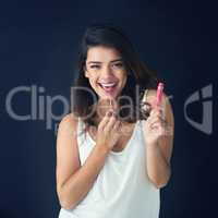 Get your gloss on. Studio shot of a beautiful young woman applying lip gloss against a grey background.