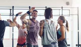 Strong people inspire other people to be strong. Shot of a group of young people motivating each other with a high five in a gym.