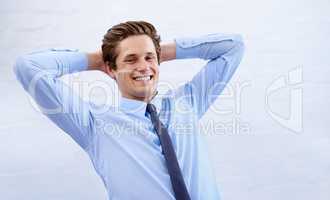 Satisfied with his success. A satisfied young businessman leaning back with his hands behind his head.
