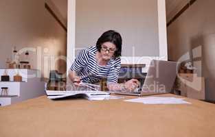 There is no substitute for hard work. A cropped shot of a woman standing at her desk and working on her laptop.