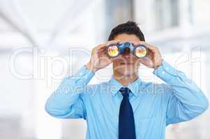 Business vision. Portrait of young business man seeking through binoculars.