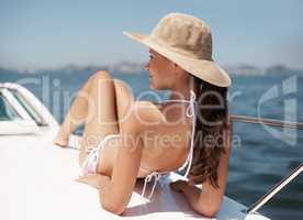 Catching the rays. An attractive young woman tanning on the deck of a luxury yacht.