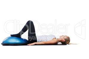 Working up a sweat. A young woman using a bosu-ball to work out.