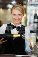 Elegance, style and grace. Portrait of a barmaid pouring champagne for a special celebration.