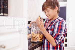 Moms biscuits are the best. A young boy reaching for a cookie from the jar.