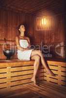 This is her bliss. Full length shot of a young woman relaxing in the sauna at a spa.