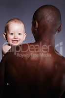 Safe and secure in his arms. Portrait of a cute little boy being held by an adult male.