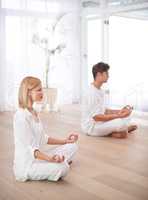 On their way to enlightenment.... Two people sitting in the lotus position in a yoga studio.
