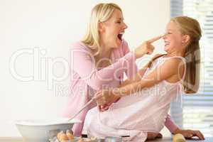 Got you. A mother playfully putting flour on her daughters nose while baking together.