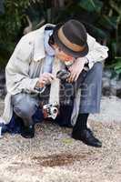 Hes got a keen investigative eye. Curious private investigator looking through a magnifying glass at the ground for clues.