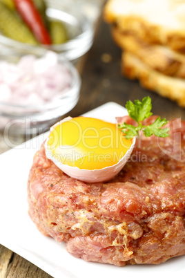 Steak Tartar mit offenem Ei auf Holz