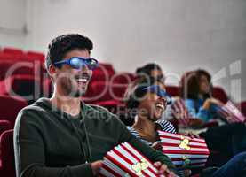 Thrills and spills never looked this good. Shot of a man and woman laughing while watching a 3D movie at the cinema.