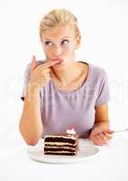 Trying a small taste.... Young woman tasting the frosting of a delicious piece of chocolate cake.