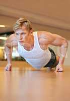 Focused on working out his upper body. Fit young man doing push ups in a health club.