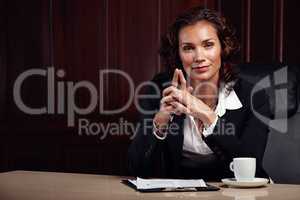 Lets begin. Attractive mature female advocate sitting with her hands clasped together while smiling at the camera.