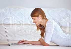 Browsing the internet for blogging tips. Cropped shot of an attractive young woman using a laptop while lying down on the floor in her bedroom.