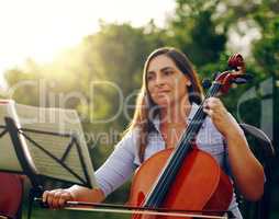 Music is something you hear and feel. Cropped shot of a beautiful woman playing a cello in the backyard.