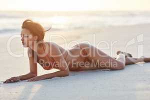 The beach only adds to my sexiness. Shot of a beautiful young woman lying on the beach.