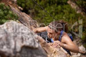 Shes determined to reach the top. Shot of a young woman climbing a mountain rockface.