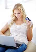 Digital shopaholic. Young woman relaxed at home as she shops online.
