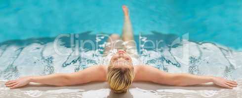 Relax, unwind and get into a blissful state of mind. Rearview shot of a young woman relaxing in the pool at a spa.