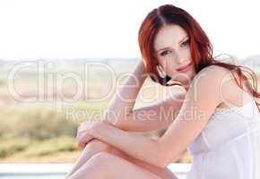 Beauty that takes the breath away. A young redheaded woman sitting outside.
