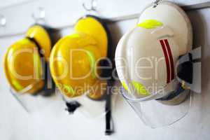 Protected against work hazards. Shot of firemens helmets hanging from a wall.