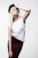 Its all about my style. A trendy young blonde model wearing a bowler hat while isolated on white and striking a pose.