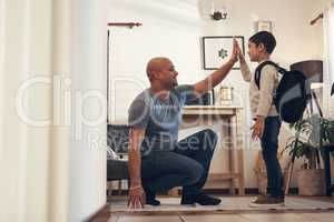 Raise them good, praise them good. Shot of an adorable little boy giving his father a high five before leaving to go to school.