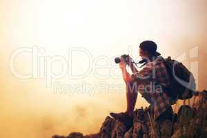 Photography is a love affair with nature. Shot of a young photographer taking a picture of a foggy landscape from the top of a mountain.