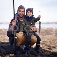 One point for me none for dad. Portrait of a cute little boy holding the fish he caught with his dad.