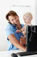 Ive got an important message for you Dad. Shot of a father at his desk holding a small child while talking on the phone.