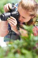 Focusing on nature photography. A gorgeous young woman focusing through the lens of her camera.