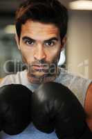 Hes ready to take on any competitor. Portrait of a focused man wearing boxing gloves and sport clothing posing ready to fight.
