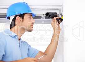 Taking care of your security needs. Shot of a handsome young man installing a security camera.