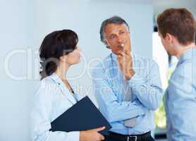 Thoughtful business man listening to his colleague. Portrait of mature business man listening carefully to colleague with woman in office.