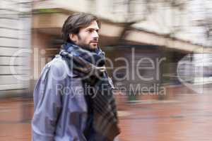 City life can be fast-paced. A handsome man walking through an urban area in a hurry.
