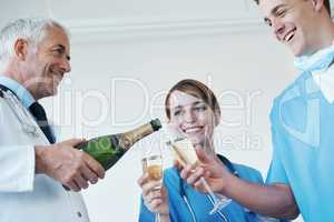 Cheers to a successful procedure. A general practitioner, nurse and surgeon drinking champagne together after a successful procedure.