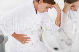 Struggling with morning sickness. A pregnant woman struggling with morning sickness in the bathroom.