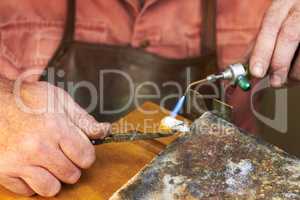 Applying heat - Jewelry manufacturing. Cropped view of a manufacturing jeweler at work with a small acetylene torch.