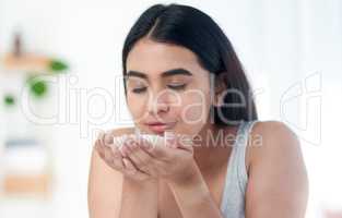 Im about to smell amazing. Shot of young woman smelling some skincare product.