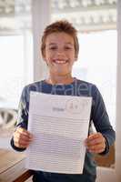 Check this out. Shot of a proud young boy holding up his essay that got him an A+.