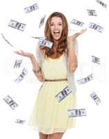 Collecting her winnings. Portrait of an ecstatic young woman standing in studio with money dropping around her.