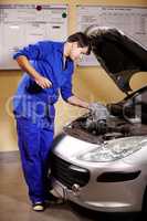 The oil seems to be fine. A male mechanic wiping off the oil stick to measure a cars oil.