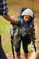Lending a helping hand. Young woman receiving a helping hand from her boyfriend while out hiking.