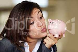 Cash is a girls best friend. An attractive businesswoman pulling a kissing face at her piggybank.