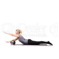 Her workout yields results. A young woman using an exercise ball while lying down - isolated.