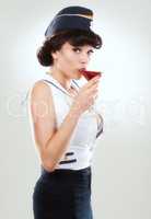 Taking off the edge. Image of a stunning woman dressed up as a sailor girl and drinking a martini.
