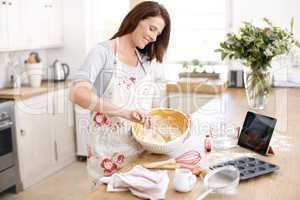 Stirring to perfection. An attractive mature woman stirring cake mix in the kitchen.